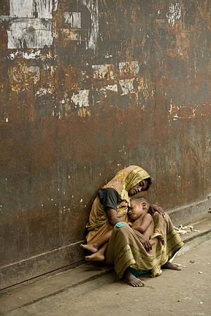 Mother and Child Resting Against a Weathered Rusty Wall in Street Photography HD phone wallpaper