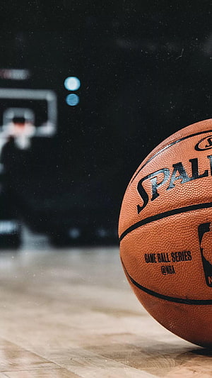 Spalding NBA Game Ball Series on a Wooden Court with Blurred Hoop Background HD phone wallpaper