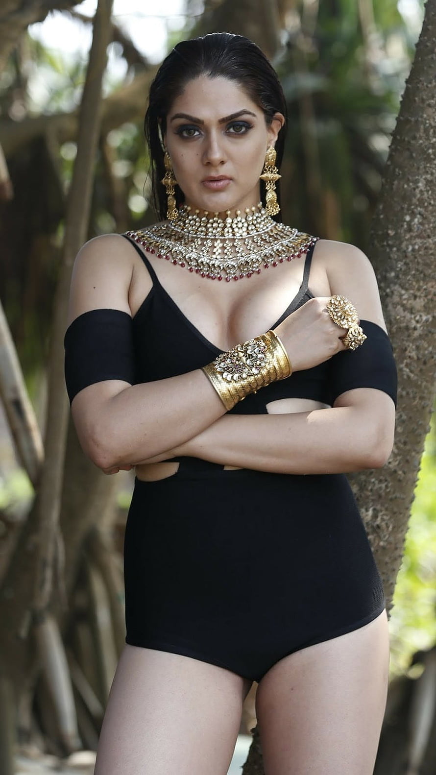 Adah Sharma in a black bodysuit with traditional gold jewelry posing outdoors HD phone wallpaper
