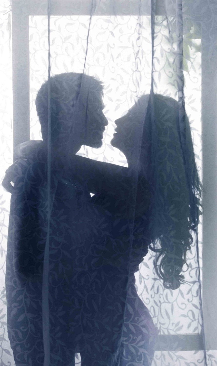 Silhouetted Couple Embracing Behind Sheer Floral Curtain in Soft Blue Light HD phone wallpaper