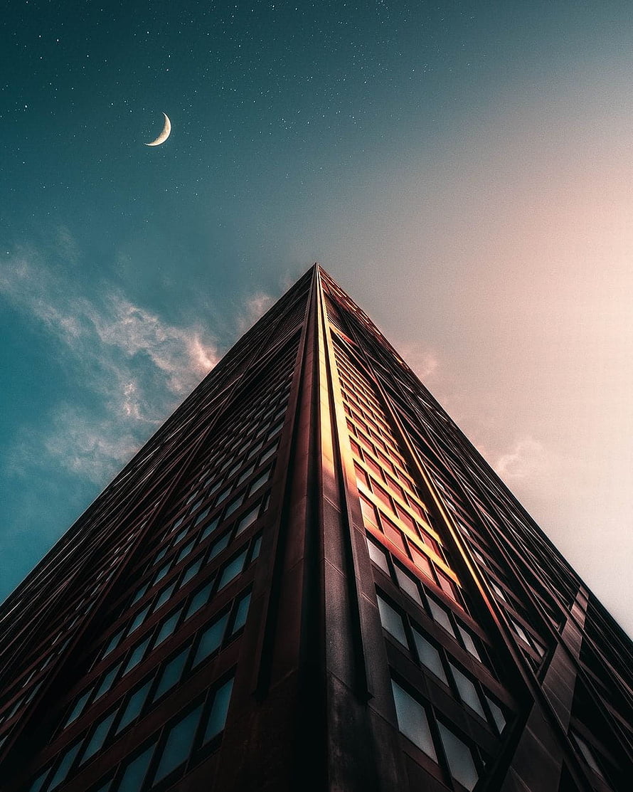 Dramatic Low-Angle View of a Modern Skyscraper Against a Starry Twilight Sky with a Crescent Moon HD phone wallpaper