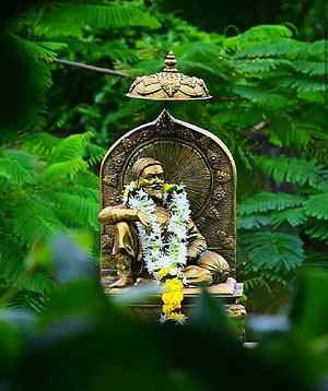 Shivaji Maharaj Bronze Statue Adorned With White Flower Garland in Lush Green Garden Setting HD phone wallpaper