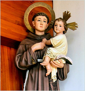 Saint Anthony of Padua statue holding the Christ Child with golden halos and rosary beads HD phone wallpaper