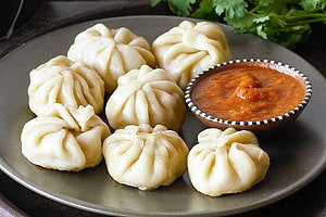Steamed Chicken Momos with Spicy Tomato Chutney on a Ceramic Plate HD wallpaper