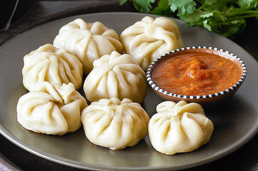 Steamed Chicken Momos with Spicy Tomato Chutney on a Ceramic Plate HD wallpaper