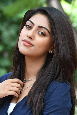 Anu Emmanuel Portrait With Long Dark Hair And Layered Necklace Against Green Foliage HD phone wallpaper