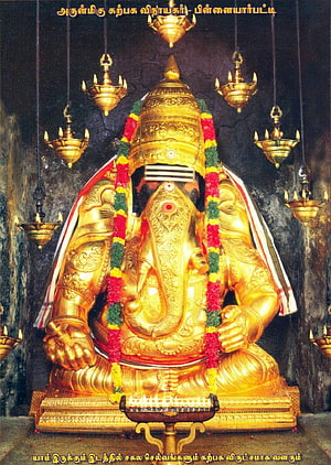 Golden Ganesha Statue at Tiruchendur Temple with Oil Lamps and Flower Garlands HD phone wallpaper