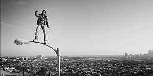 Kendrick Lamar Standing on Streetlight Overlooking City in Black and White HD wallpaper
