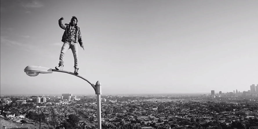 Kendrick Lamar Standing on Streetlight Overlooking City in Black and White HD wallpaper