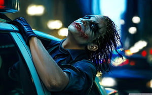 The Joker Leaning Against a Car in a Dark Urban Setting HD wallpaper