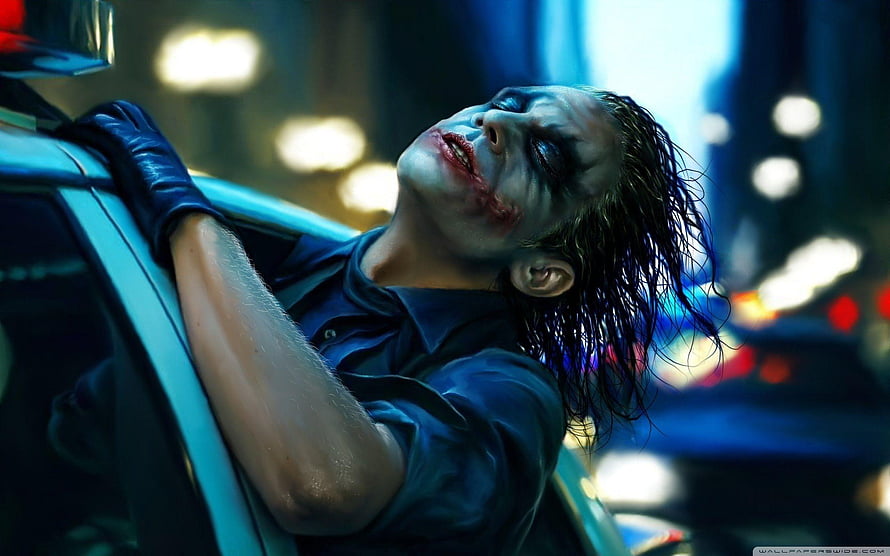 The Joker Leaning Against a Car in a Dark Urban Setting HD wallpaper