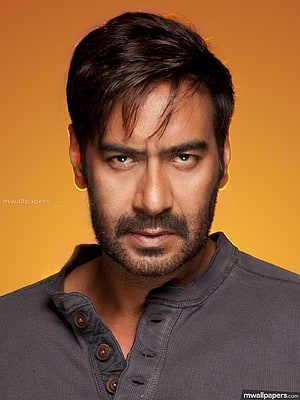 Ajay Devgan Intense Portrait Against Warm Orange Background HD phone wallpaper