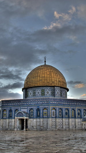 Dome of the Rock in Jerusalem with golden dome and intricate blue tilework under dramatic cloudy sky HD phone wallpaper