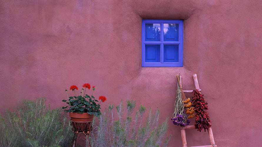 Vibrant Blue Window on Pink Adobe Wall with Potted Geraniums and Dried Chilies HD wallpaper