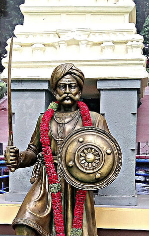 Bronze Statue of Kempegowda Holding Sword and Shield with Red Floral Garland HD phone wallpaper