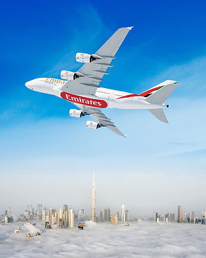 Emirates A380 Airplane Soaring Above Dubai Skyline and Burj Khalifa in Clear Blue Sky HD phone wallpaper