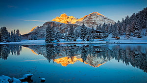 Serene Winter Lake Reflection of Snow-Covered Mountains and Pine Forests at Golden Hour HD wallpaper