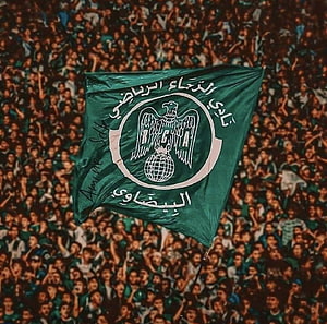 Raja Club Athletic Green Flag With Eagle Emblem Held Above a Dense Stadium Crowd HD wallpaper