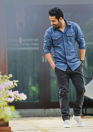 Actor Varun Dhawan in a casual blue denim shirt and dark jeans posing outdoors HD phone wallpaper