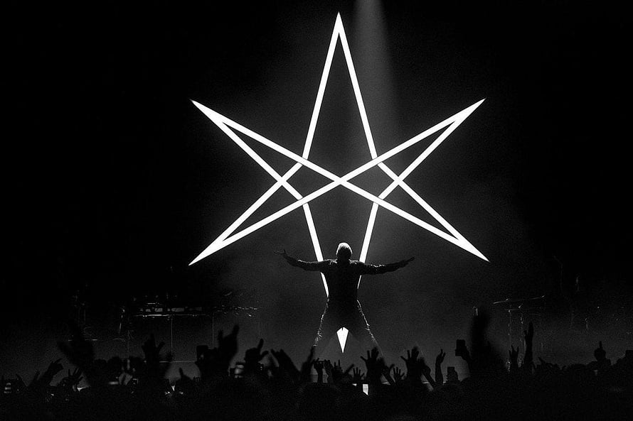 Silhouette of a performer on stage with arms outstretched in front of a giant glowing pentagram symbol HD wallpaper