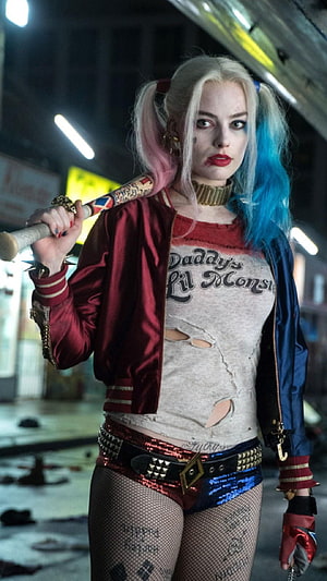 Harley Quinn in red and blue satin jacket holding baseball bat in gritty urban setting HD phone wallpaper
