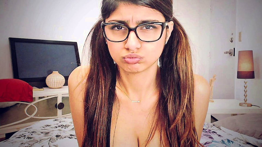 Young woman with long dark hair and black-rimmed glasses making a playful pouty expression in a bedroom, The Mia Khalifa diss song you didn't know you needed – Curated Flame HD wallpaper