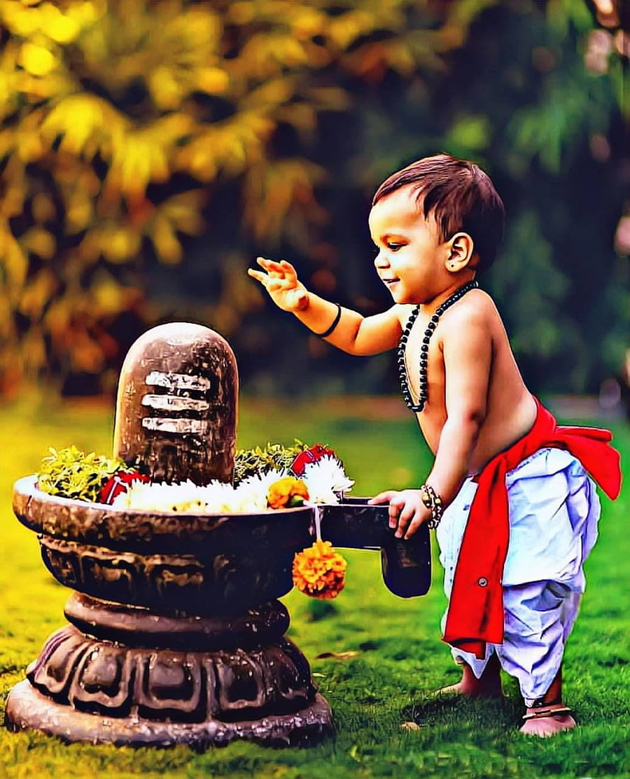 Cute toddler boy performing puja at a Shiva Lingam with flowers and water in a garden HD phone wallpaper