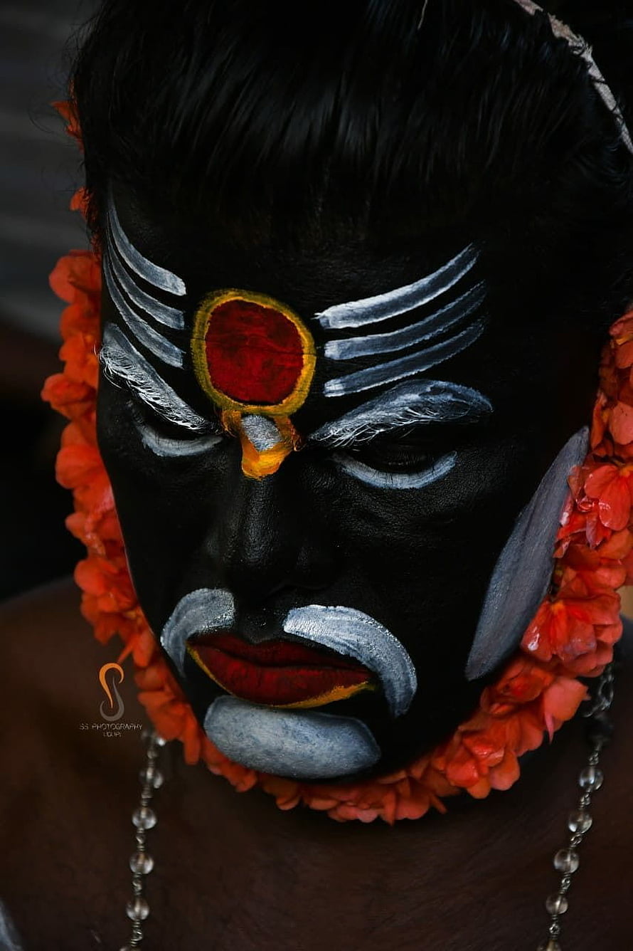 Close-up portrait of a performer in traditional black face paint with white markings and a red forehead symbol HD phone wallpaper