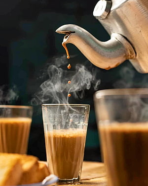 Steaming Indian Chai Pouring from a Traditional Kettle into a Glass Cup HD phone wallpaper