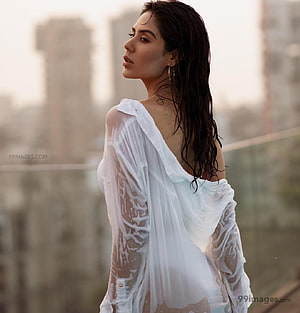 Sonam Bajwa in a sheer white blouse with wet hair against a blurred city skyline HD phone wallpaper