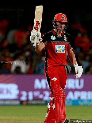 Ab de Villiers in red cricket kit raising bat in celebration on the field HD phone wallpaper