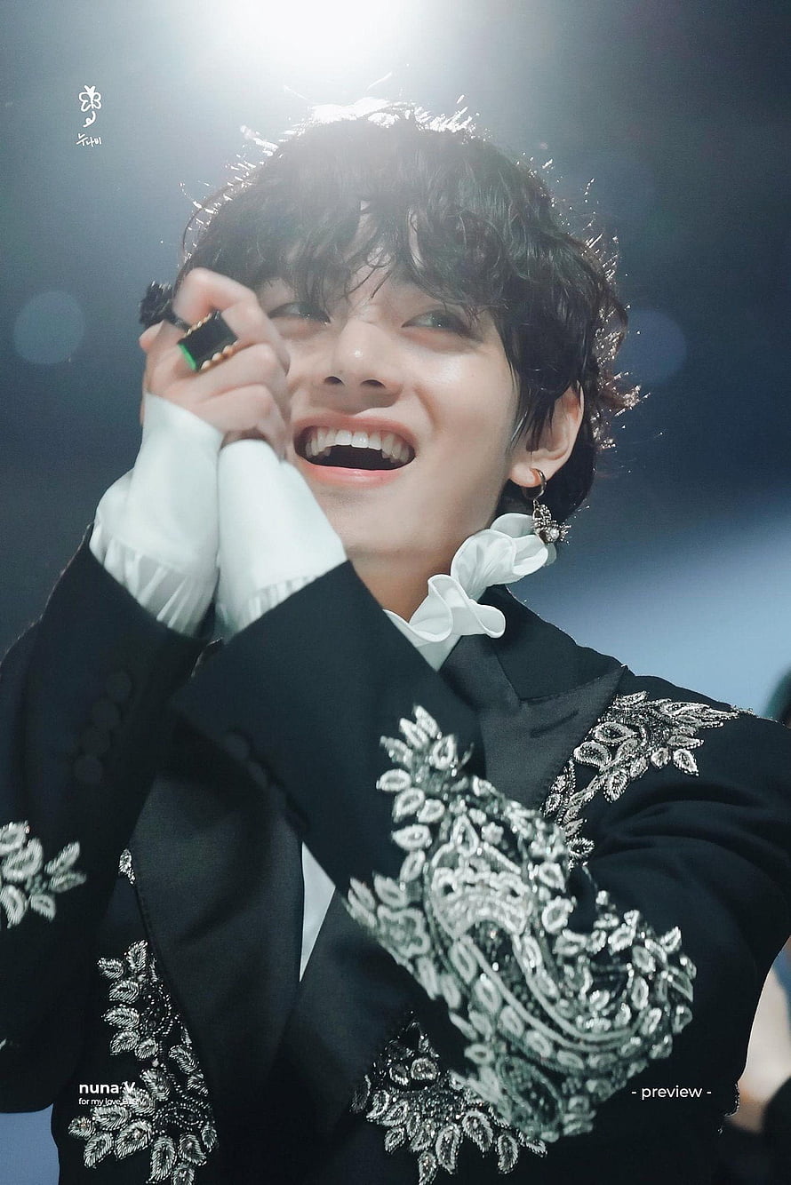V from BTS smiling brightly in an elegant black suit with silver embroidery and a white ruffled collar on stage HD phone wallpaper