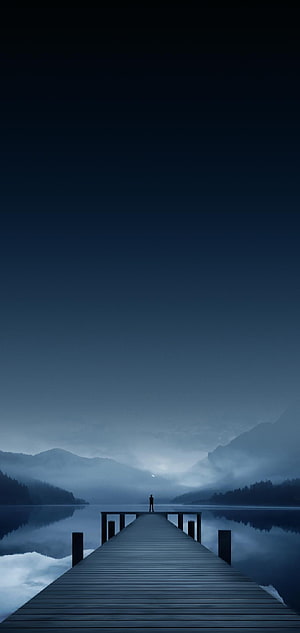 Lone Figure Standing on Wooden Dock Over Misty Lake at Dusk HD phone wallpaper