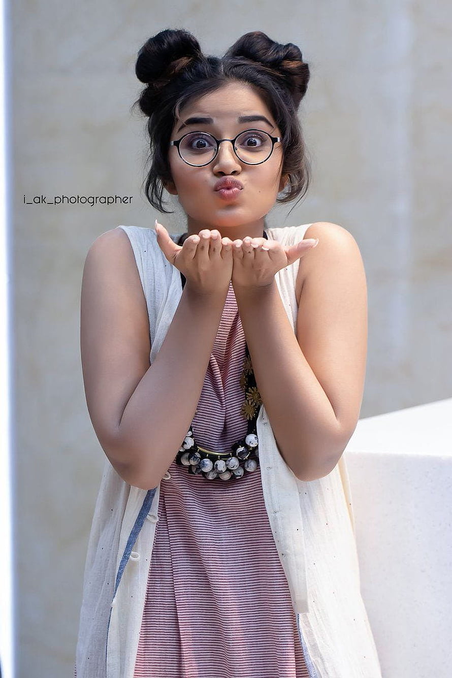 Anupama Parameswaran blowing a kiss in a striped dress and round glasses HD phone wallpaper