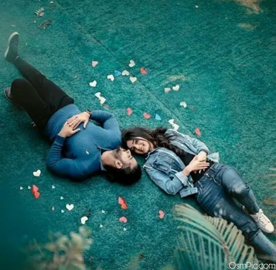 Romantic couple lying on green grass surrounded by scattered heart petals HD wallpaper