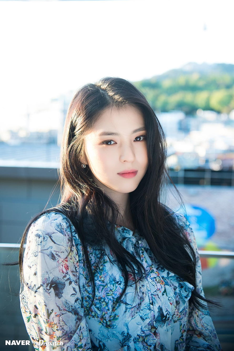 Han So Hee in a floral blouse with long dark hair against a bright outdoor backdrop HD phone wallpaper