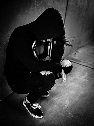 Black and white portrait of a person in a hoodie squatting in a dark alley HD phone wallpaper
