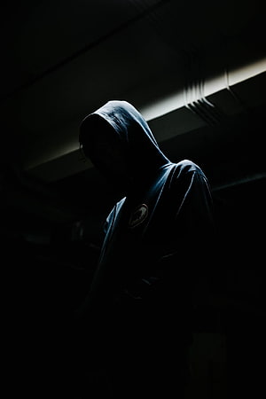 Mysterious Hooded Figure in Dark Shadows with Dramatic Lighting HD phone wallpaper
