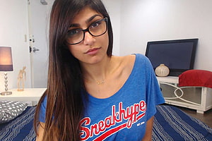 Portrait of a young woman with long dark hair wearing black glasses and a blue Sneakhype t-shirt in a bedroom, Mia Khalifa Backgrounds, #mia khalifa HD wallpaper