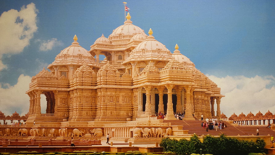 Akshardham Temple in New Delhi with intricate sandstone carvings and domed architecture under a blue sky HD wallpaper