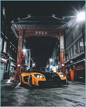 Orange and Black Nissan Skyline R34 GT-R Parked Under Traditional Chinese Archway at Night HD phone wallpaper