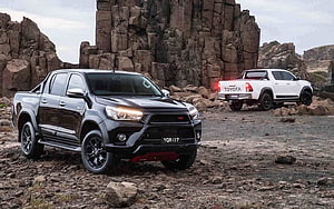 Black and White Toyota Hilux Pickups Parked on Rocky Terrain HD wallpaper