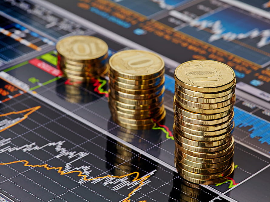 Stacks of gold coins rising over a dark financial stock market chart with orange and green trend lines HD wallpaper