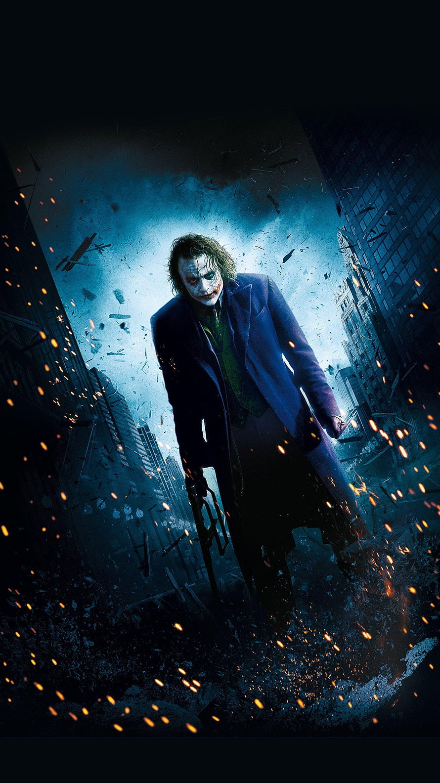 The Joker from The Dark Knight standing in a destroyed city street with flying debris and embers HD phone wallpaper