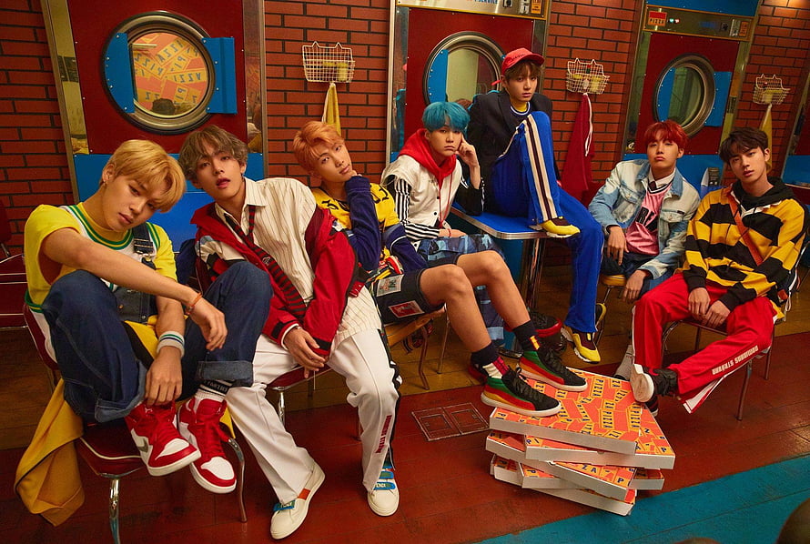 BTS Members in Colorful Streetwear Posing in Retro Laundromat Setting HD wallpaper