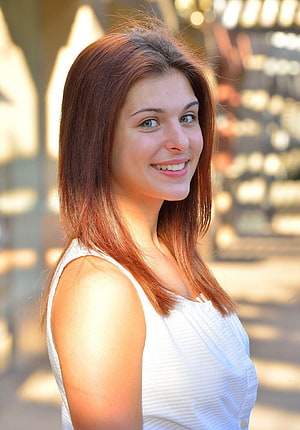 Leah Gotti smiling portrait in a white sleeveless top with warm golden hour lighting HD phone wallpaper