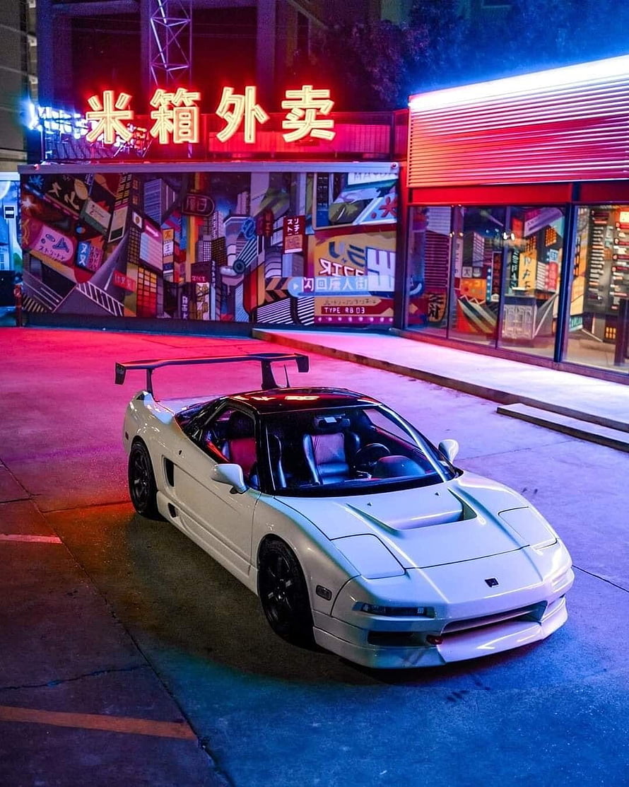 White Nissan Skyline R32 GT-R parked on a neon-lit street at night with vibrant city backdrop HD phone wallpaper
