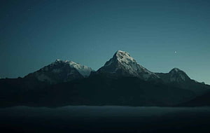 Snow-Capped Mountain Peaks Rising Above a Sea of Mist Under a Starry Night Sky HD wallpaper