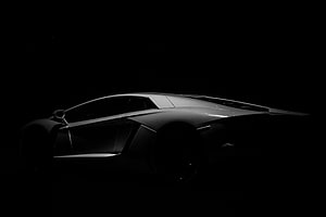 Sleek Silver Supercar Silhouette Dramatically Lit Against a Pitch Black Background HD wallpaper