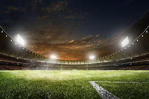 Illuminated Soccer Stadium at Night with Vibrant Green Pitch and Dramatic Sky HD wallpaper